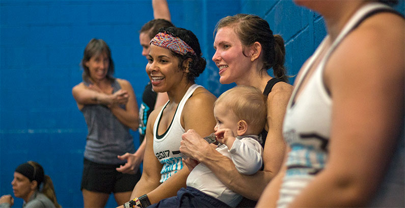 Rivalry Fitness Athletes laughing and smiling with baby after training